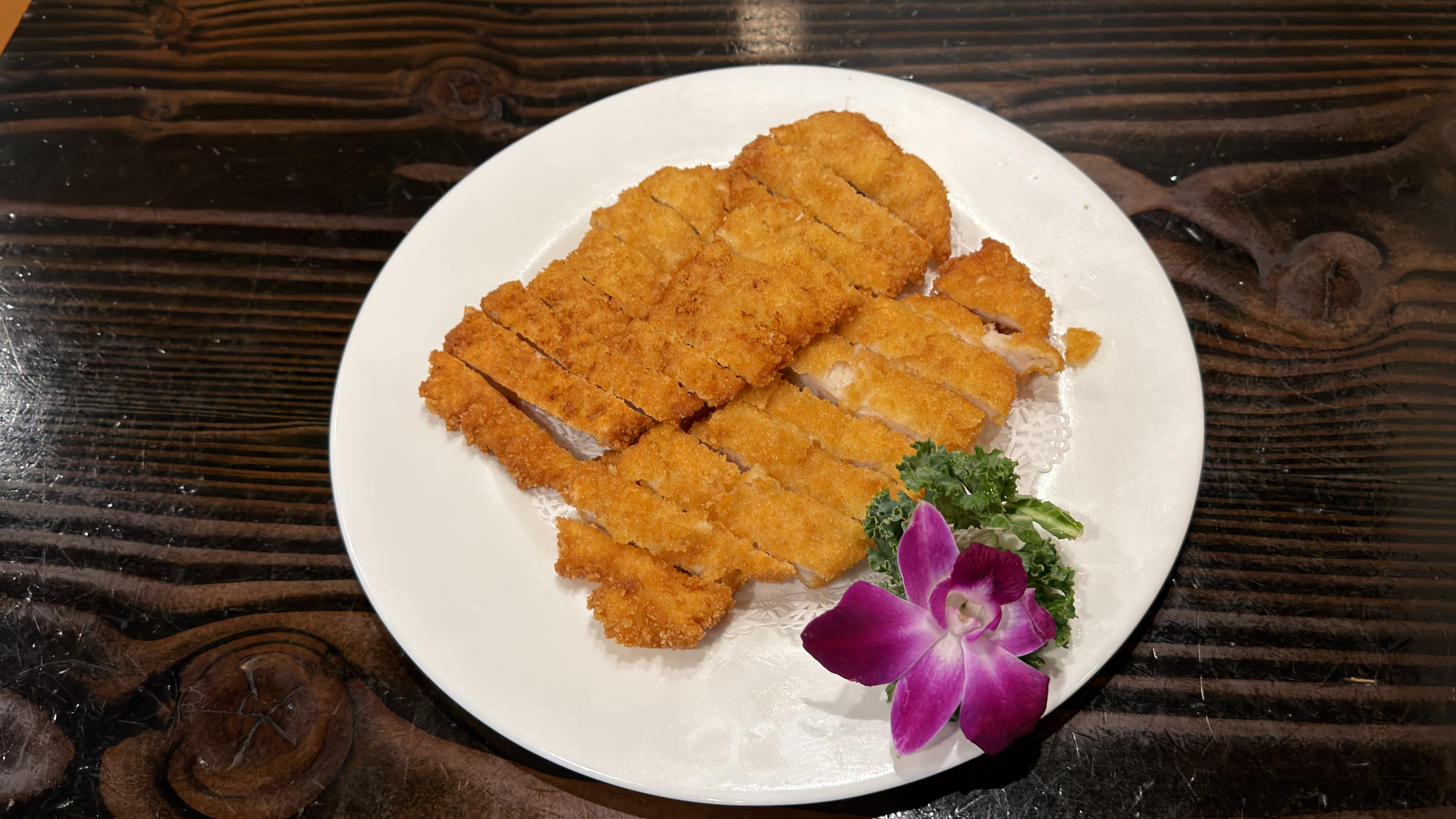 Chicken katsu sliced with orchid garnish